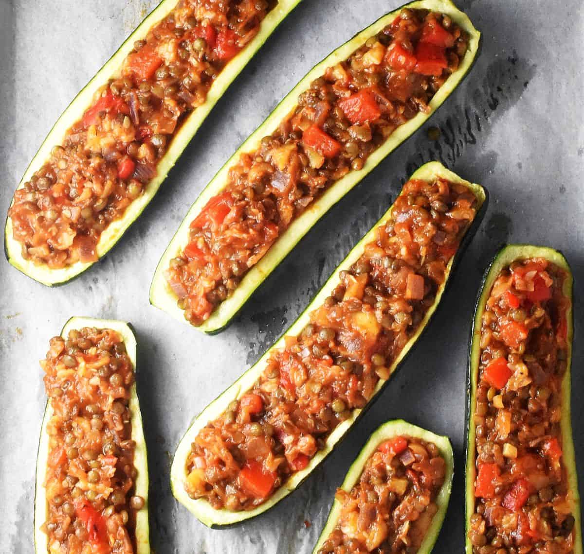 Lentil stuffed zucchini boats on top of parchment paper.