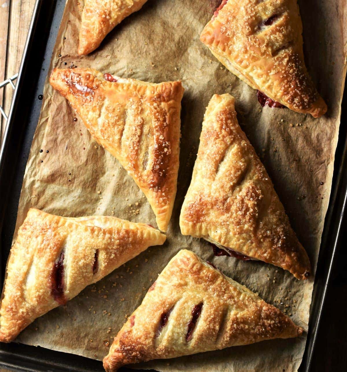 Baked strawberry turnovers on top of baking sheet lined with parchment.