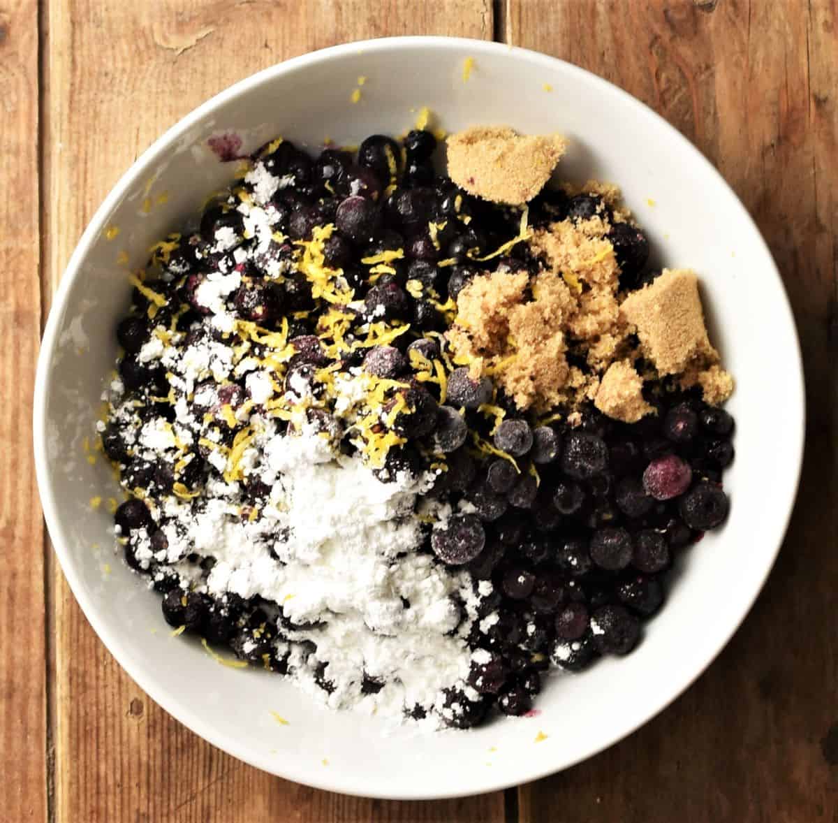 Blueberries with flour and sugar in white bowl.