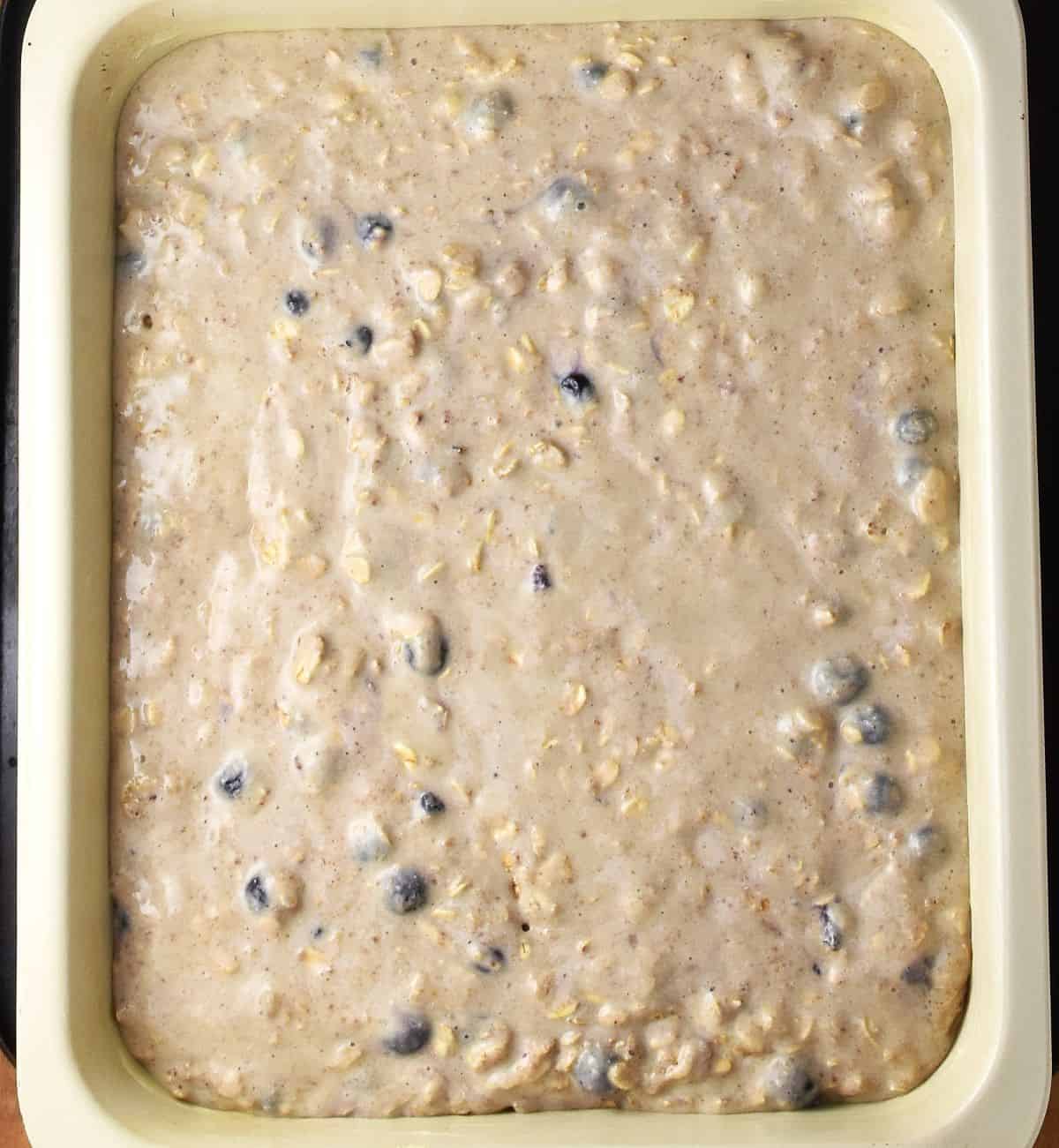 Oatmeal bake raw mixture in rectangular cream coloured pan.
