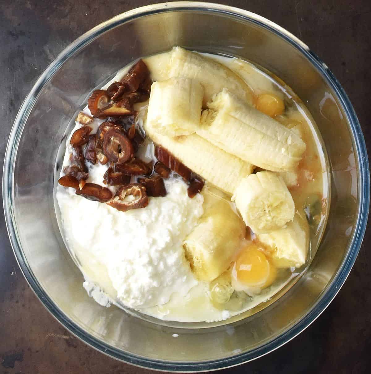 Chunks of banana and dates with eggs and cottage cheese in glass bowl.