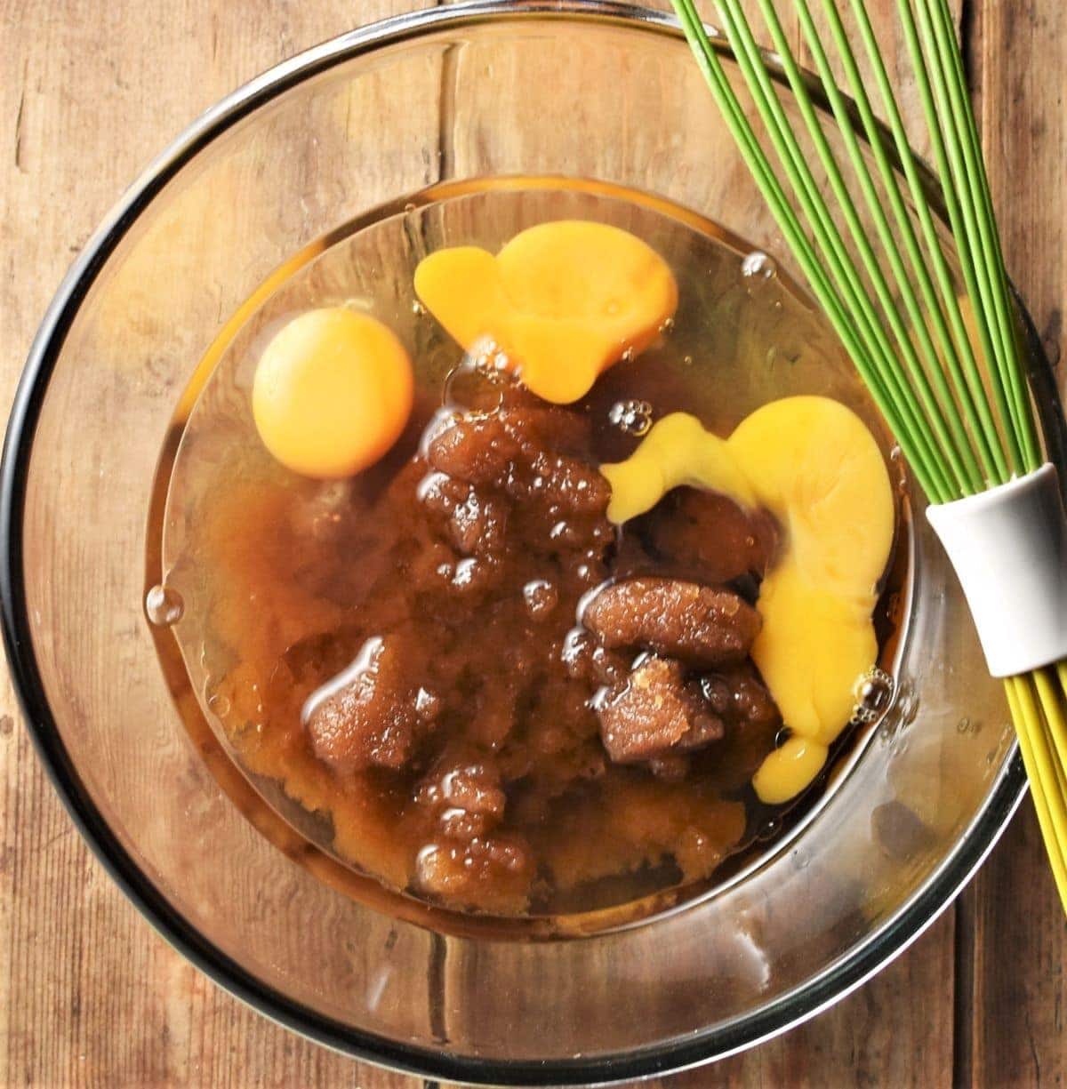 2 eggs, oil and brown sugar in mixing bowl with green whisk.