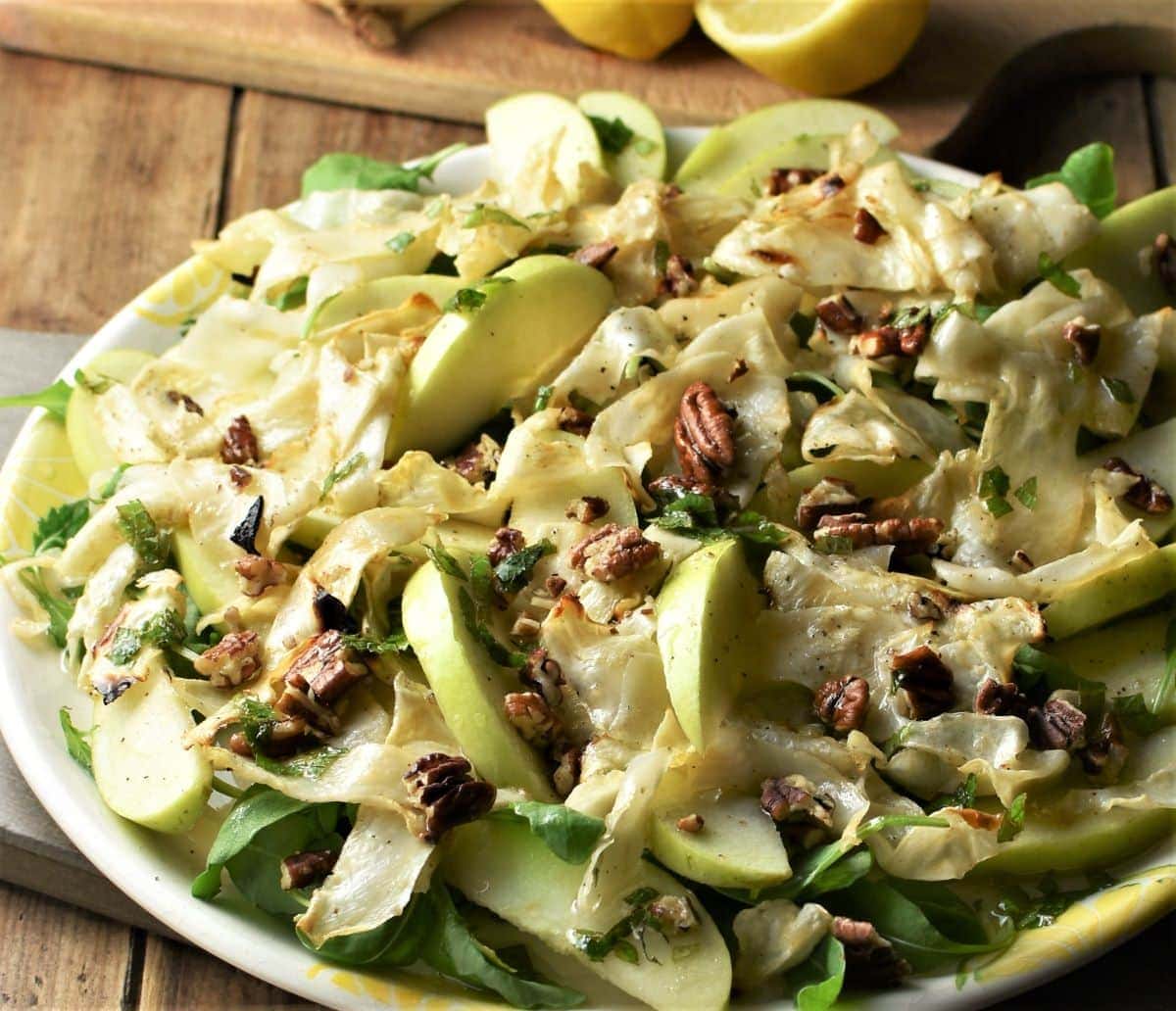 Close-up view of celeriac salad with apple and pecans on large plate.