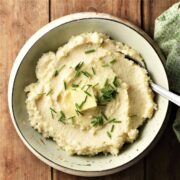 Top down view of celery root puree in green bowl with spoon.