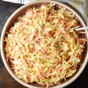 Top down view of celery root salad in rustic pink bowl with spoon.