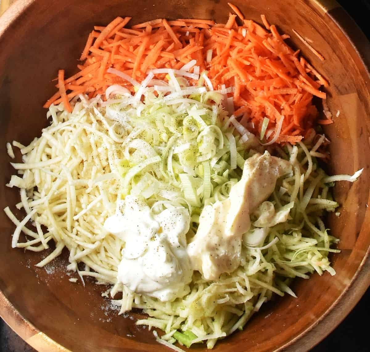 Shredded celery root, carrot and mayo in wooden bowl.