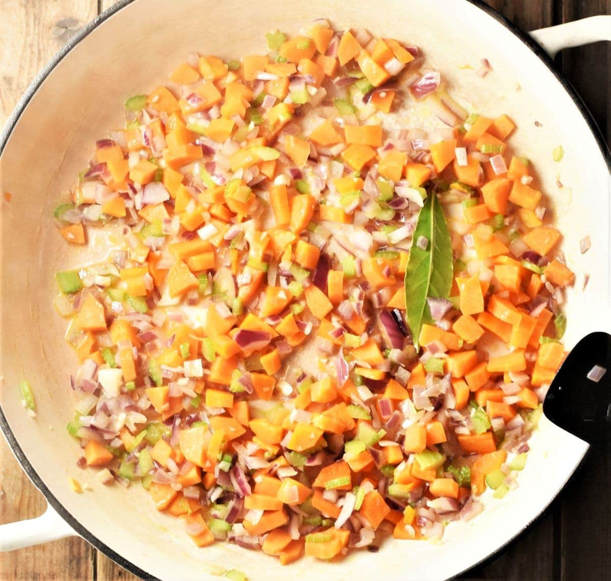 Chopped vegetables in large white pan.