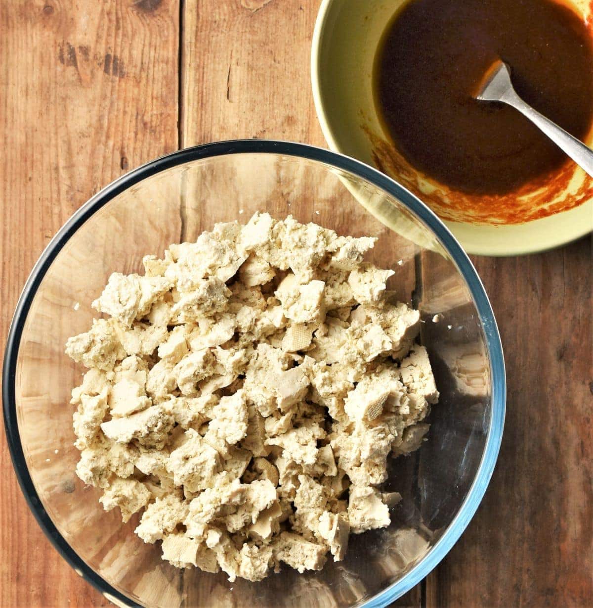 Crumbled tofu in mixing bowl and marinade in another bowl.