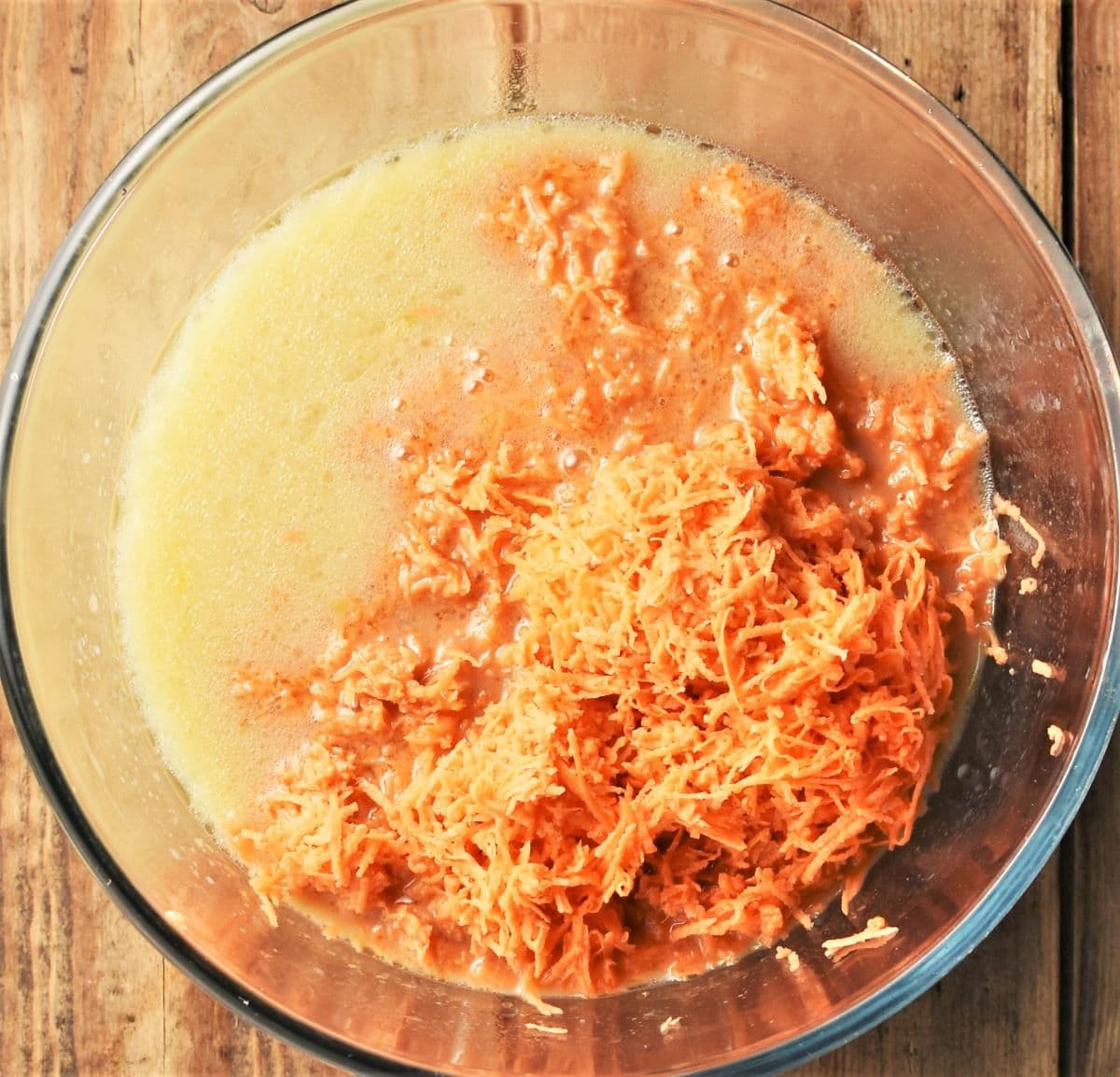 Grated sweet potato in milk mixture in bowl.