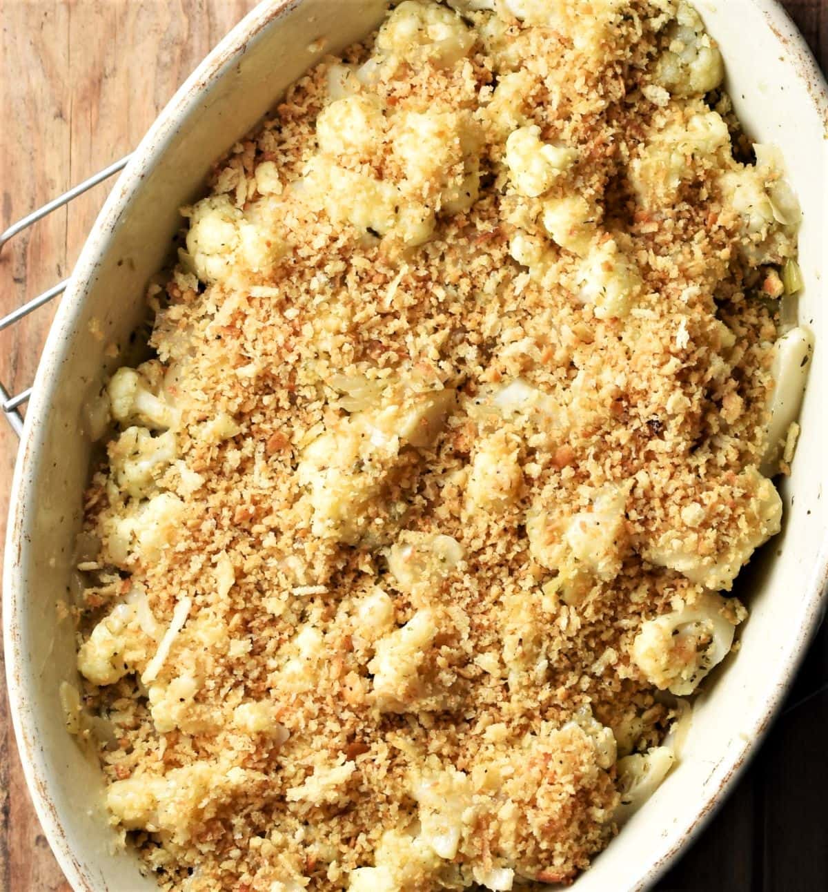 Top down view of cauliflower stuffing with breadcrumb topping in white oval dish.