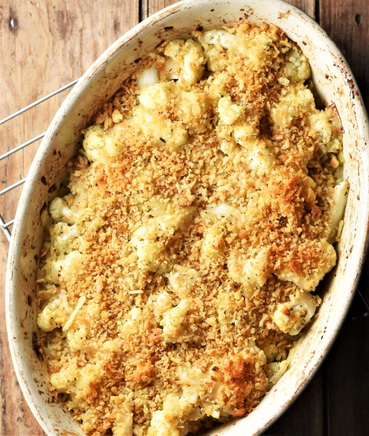 Baked cauliflower stuffing with golden breadcrumb topping in white oval dish.