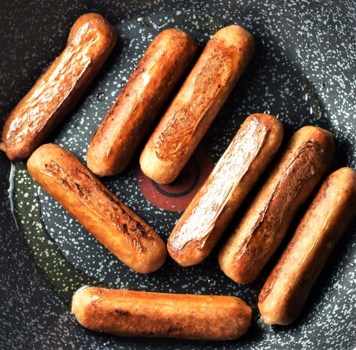 Fried sausages in pan.