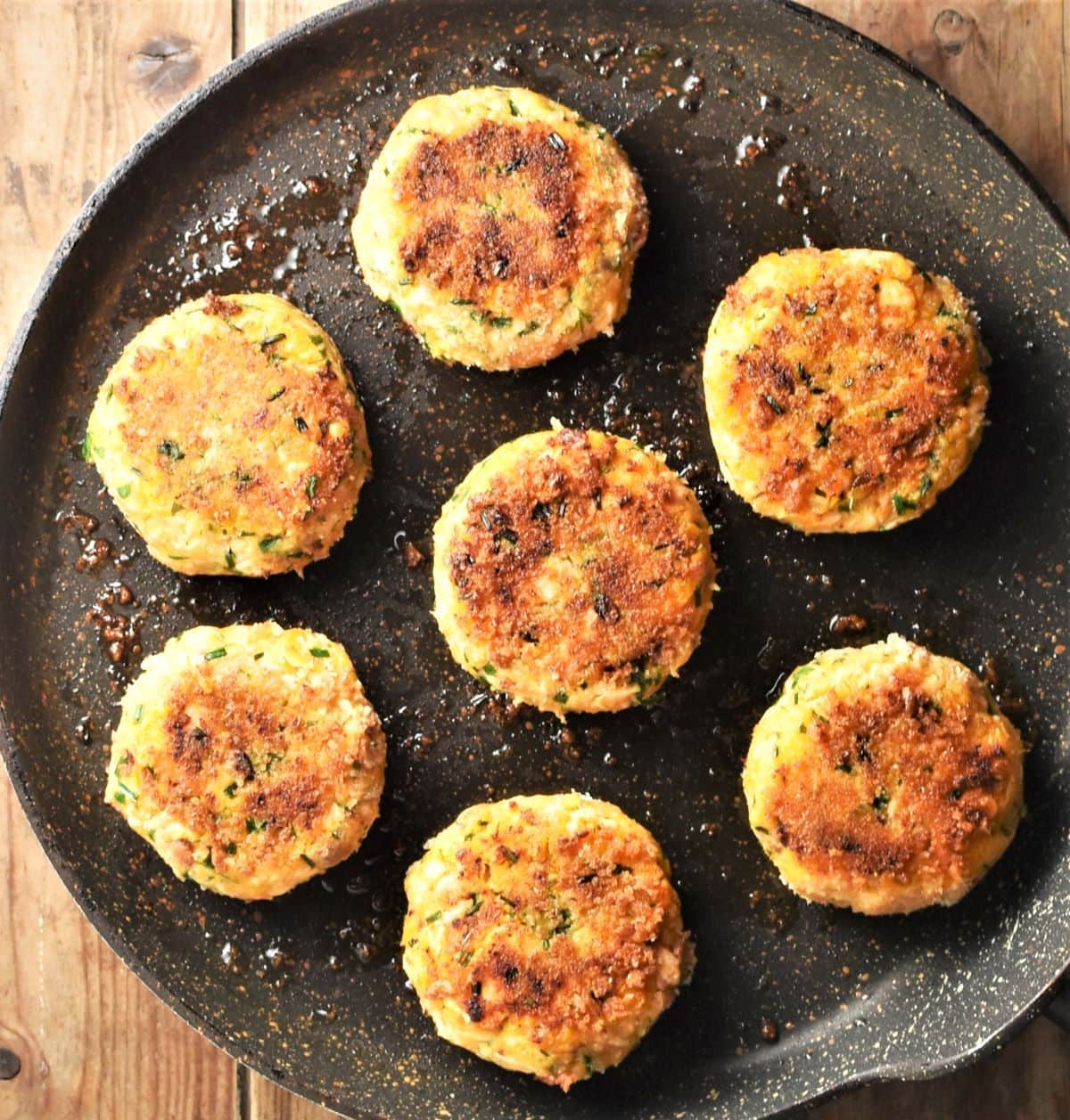 Lightly browned fish cakes on top of frying pan.