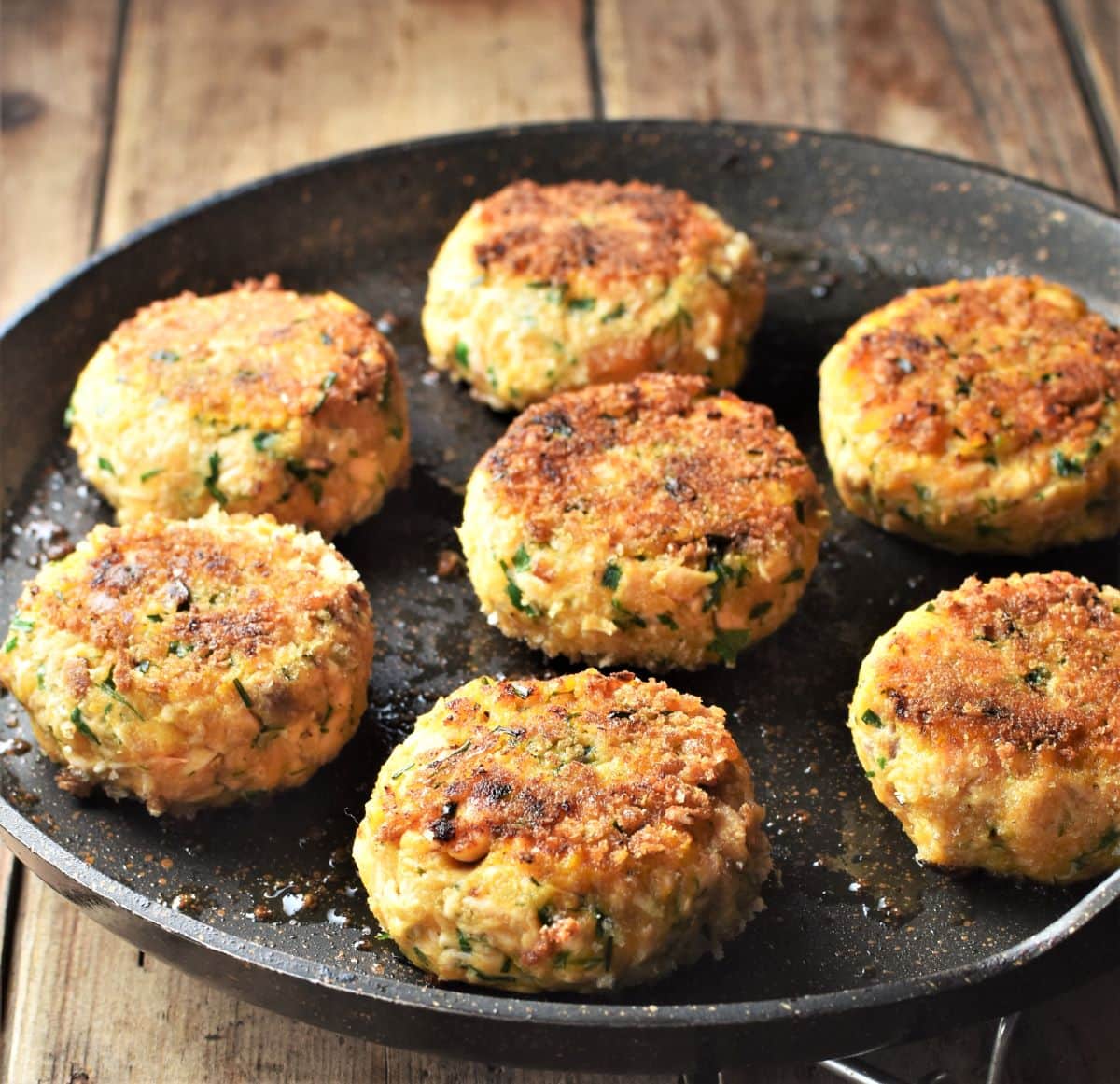 Side view of lightly browned sweet potato fish cakes in large pan.