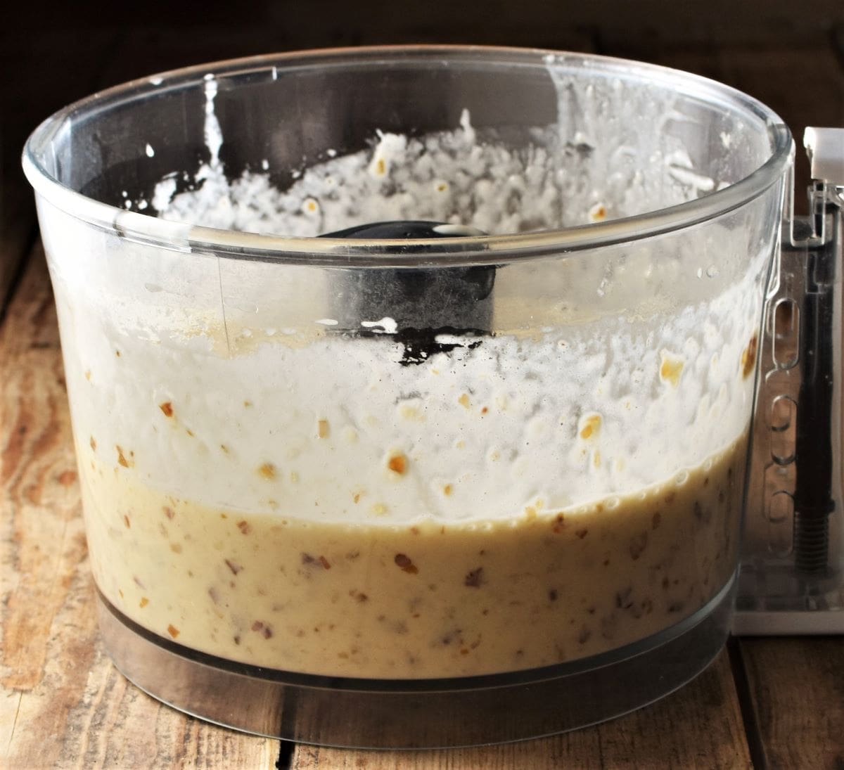 Side view of banana date bread wet mixture in food processor bowl.