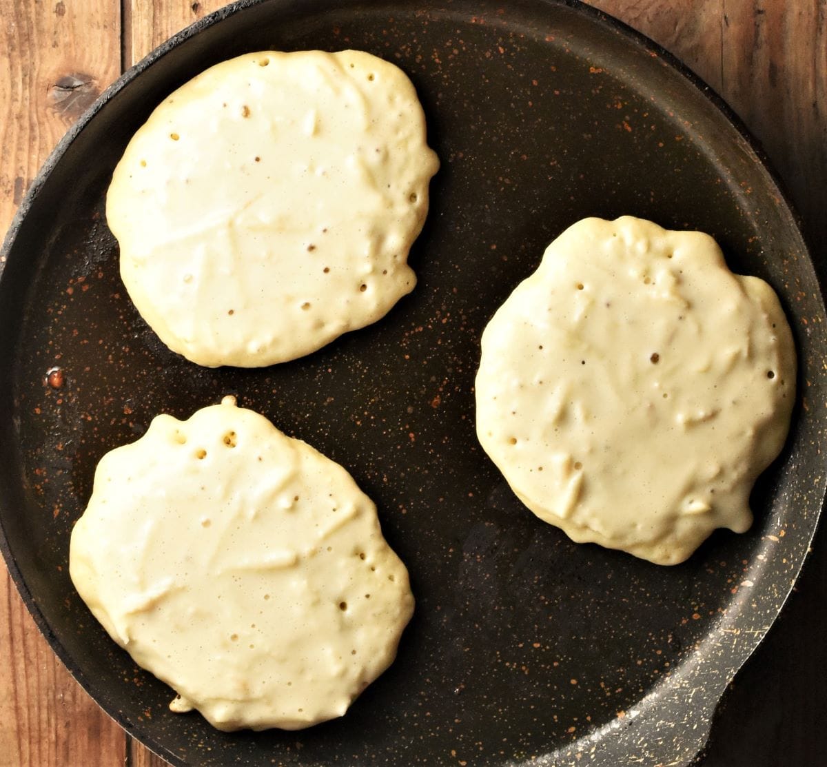 Frying 3 apple pancakes in large pan.