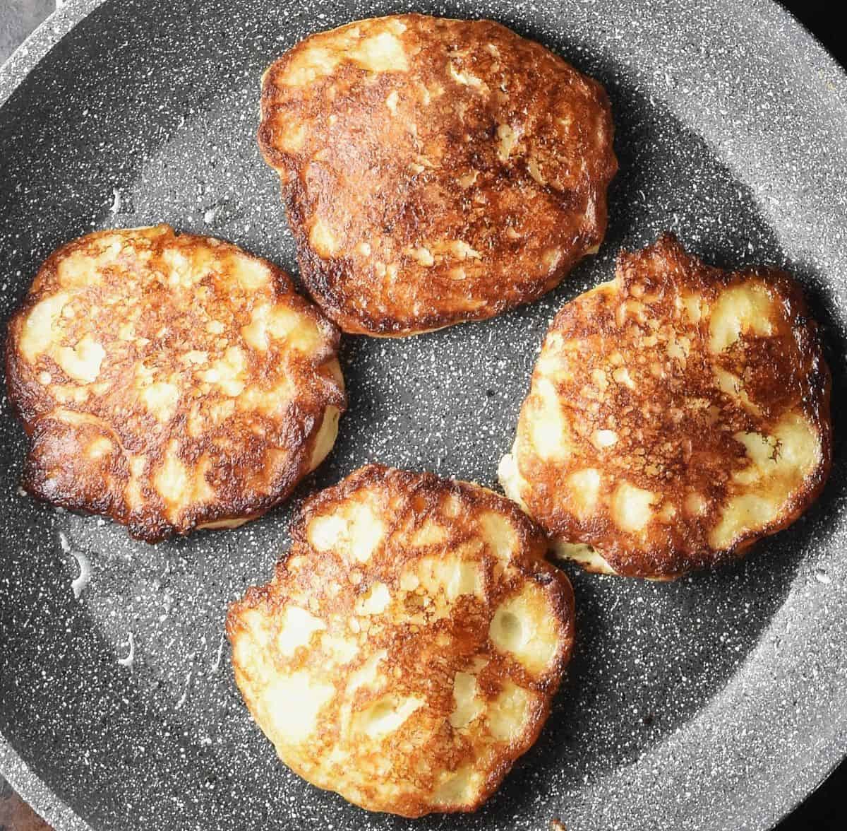 Top down view of 4 crispy Polish pancakes with apple in large pan.