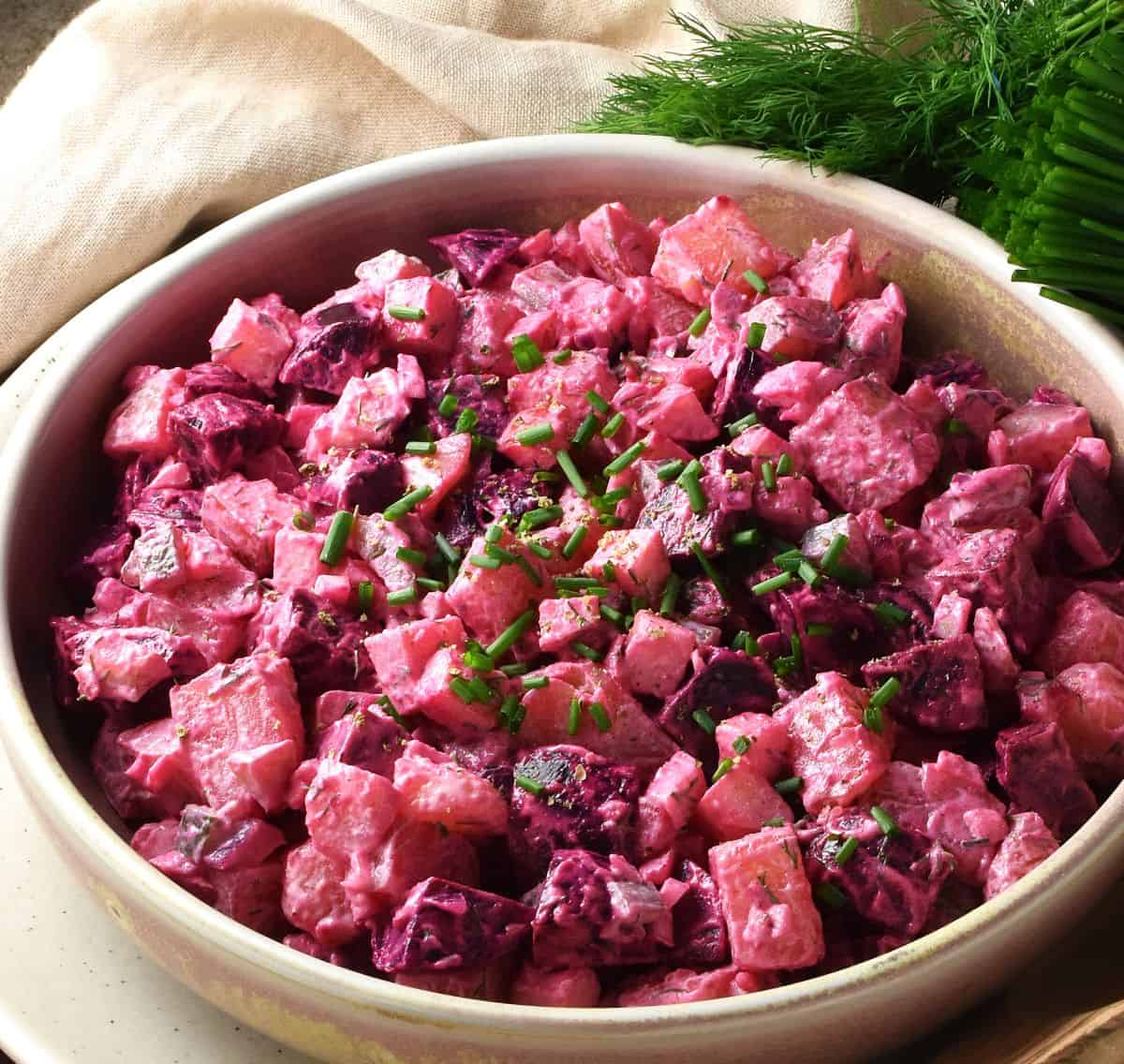 Side view of pink potato beet salad in rustic shallow bowl.