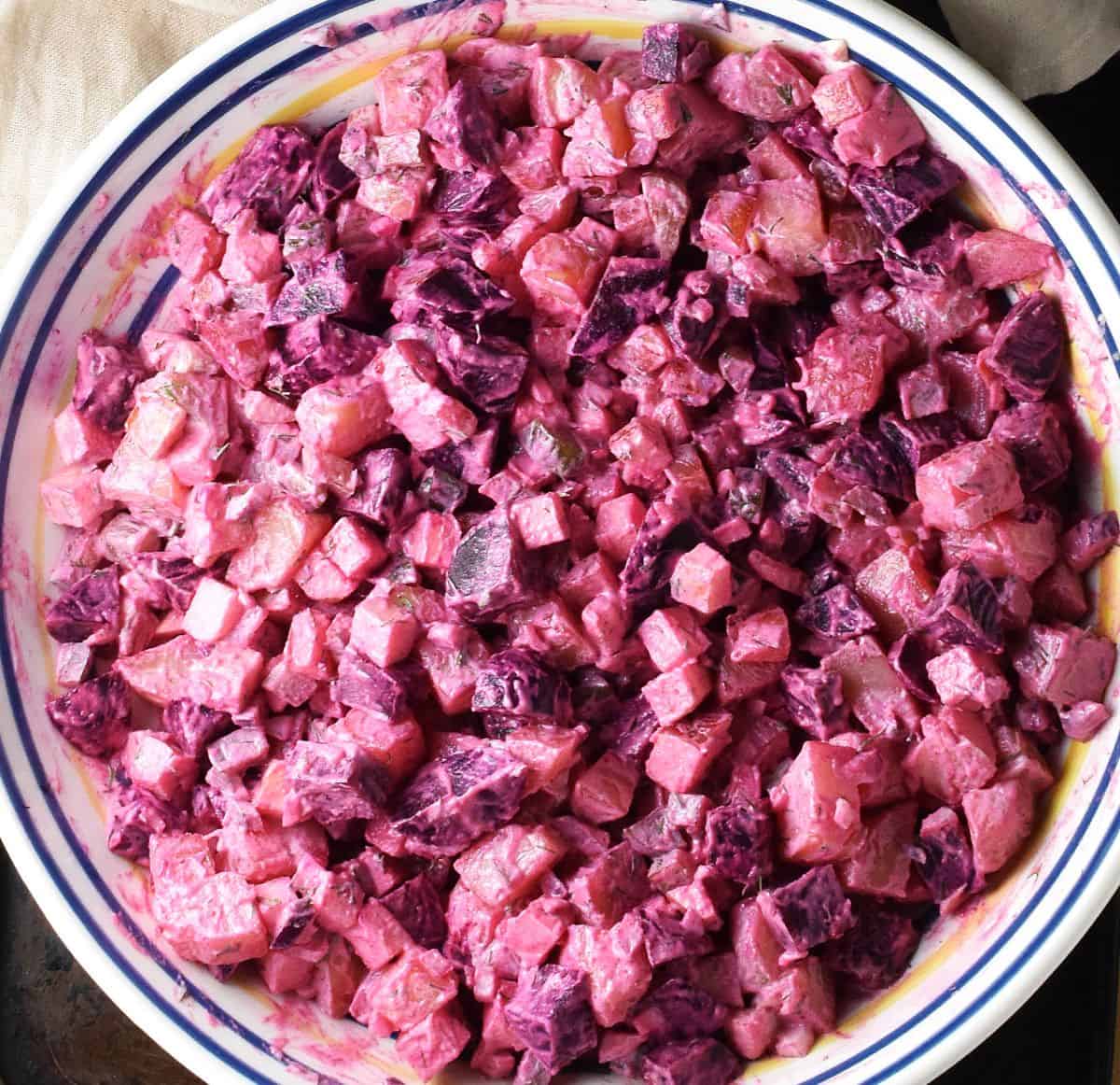 Beet and potato salad mixture in large, shallow white bowl.