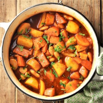 Root vegetable stew with chopped parsley in large pot.