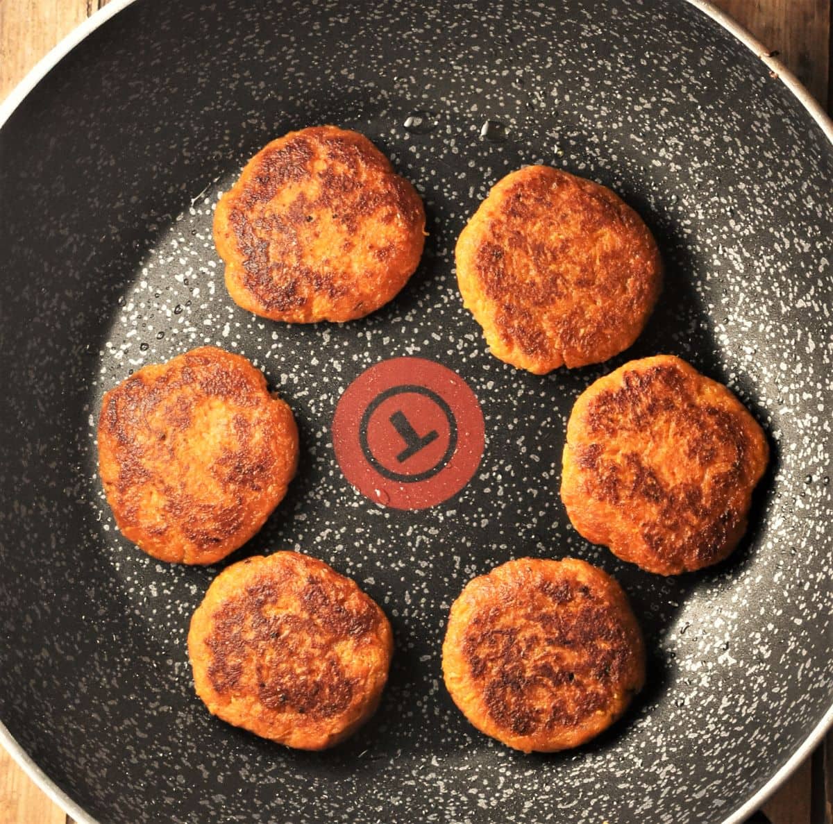 Frying sweet potato fritters in large pan.
