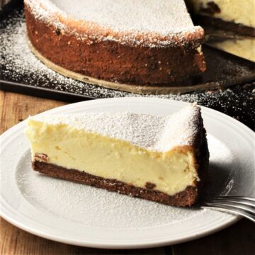 Side view of Polish cheesecake slice on top of whit plate with cheesecake in background.