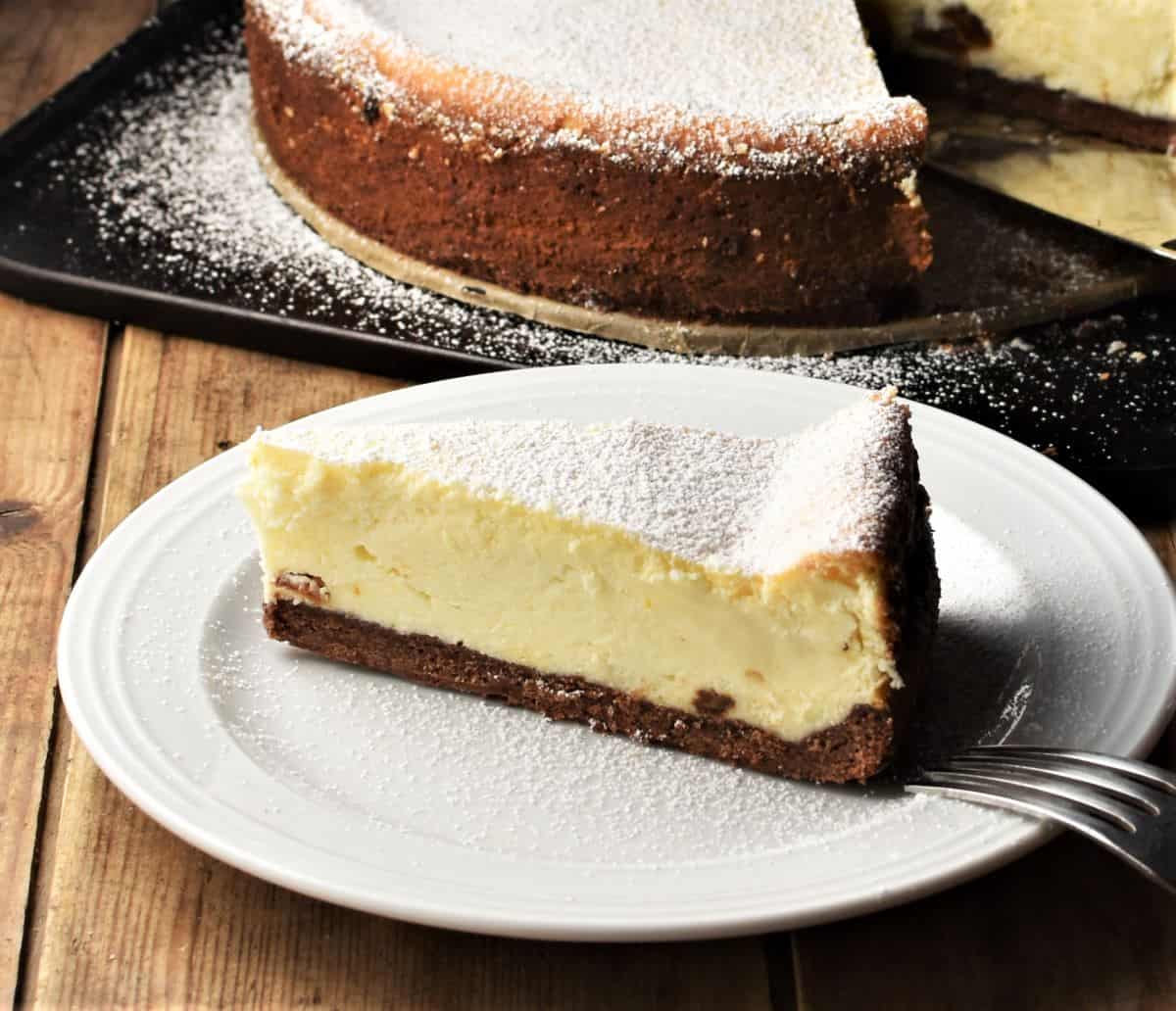 Side view of Polish sernik cheesecake on top of plate with cheesecake in background.