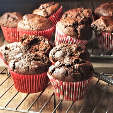Side view of healthy chocolate muffins in red cases on top of rack.