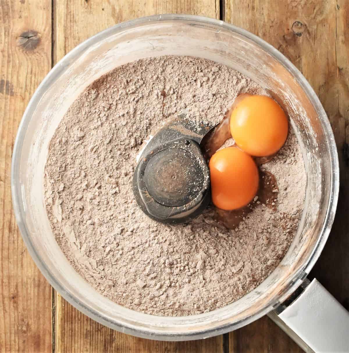 Crumbly cheesecake crust mixture and 2 egg yolks in blender bowl.