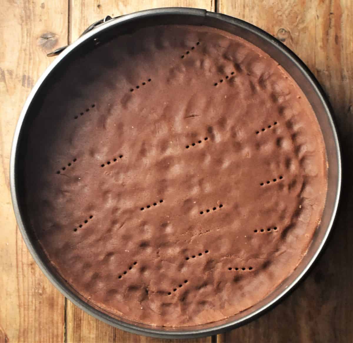 Unbaked cocoa crust inside round pan.