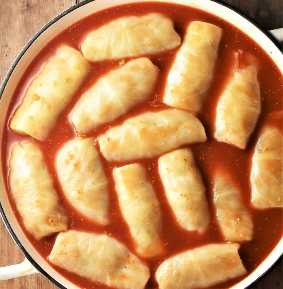 Cabbage rolls with tomato sauce in large pan.