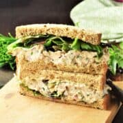 Side view of salmon salad sandwich cut in half on top of board.