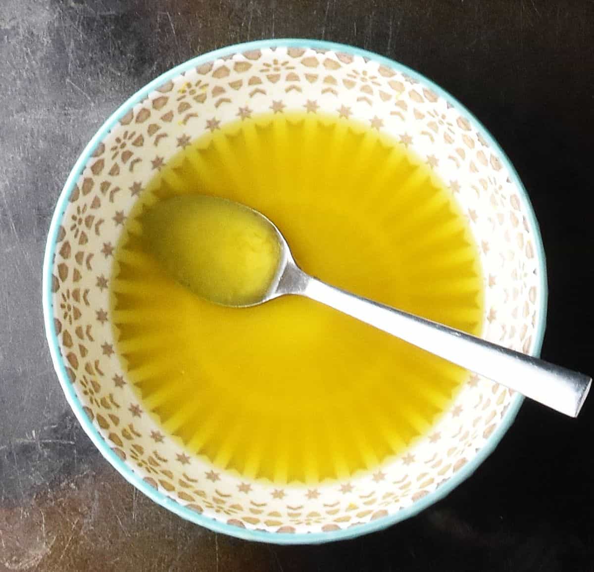 Top down view of broccoli bean salad dressing in small grey bowl with spoon.