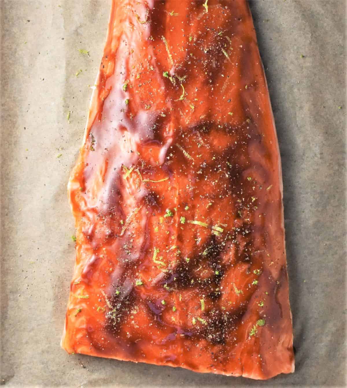 Salmon side coated in teriyaki mixture on top of parchment.