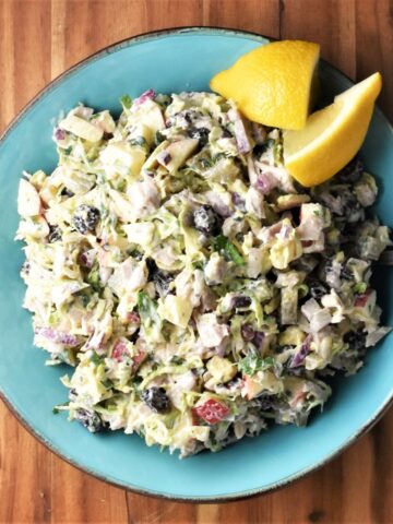 Top down view of turkey cranberry salad with lemon in blue bowl.