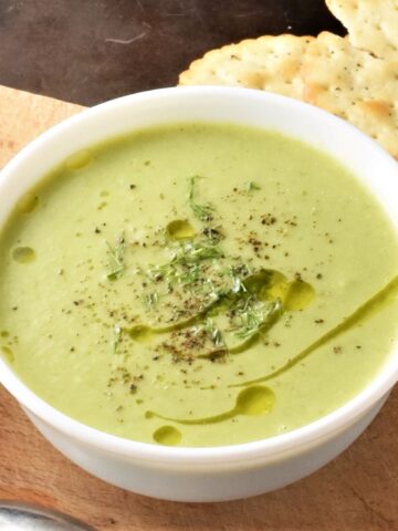 Side view of creamy brussels sprout soup in white bowl.