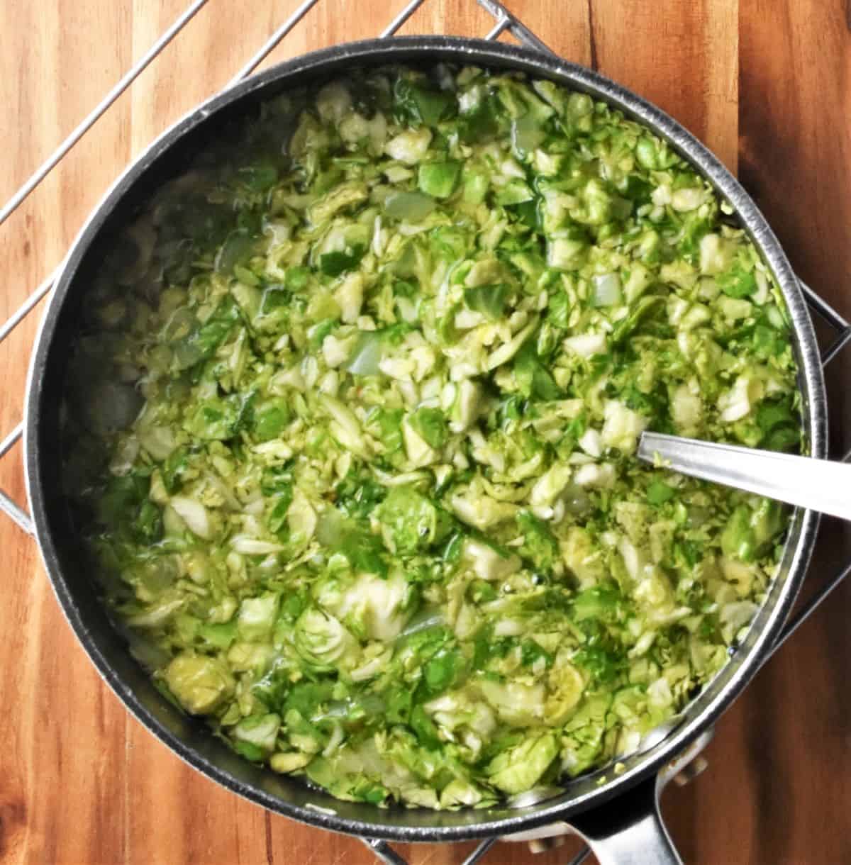 Cooking brussels sprouts soup in large pot with spoon.