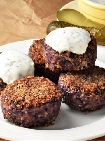 Side view of cabbage patties with yogurt sauce on plate.