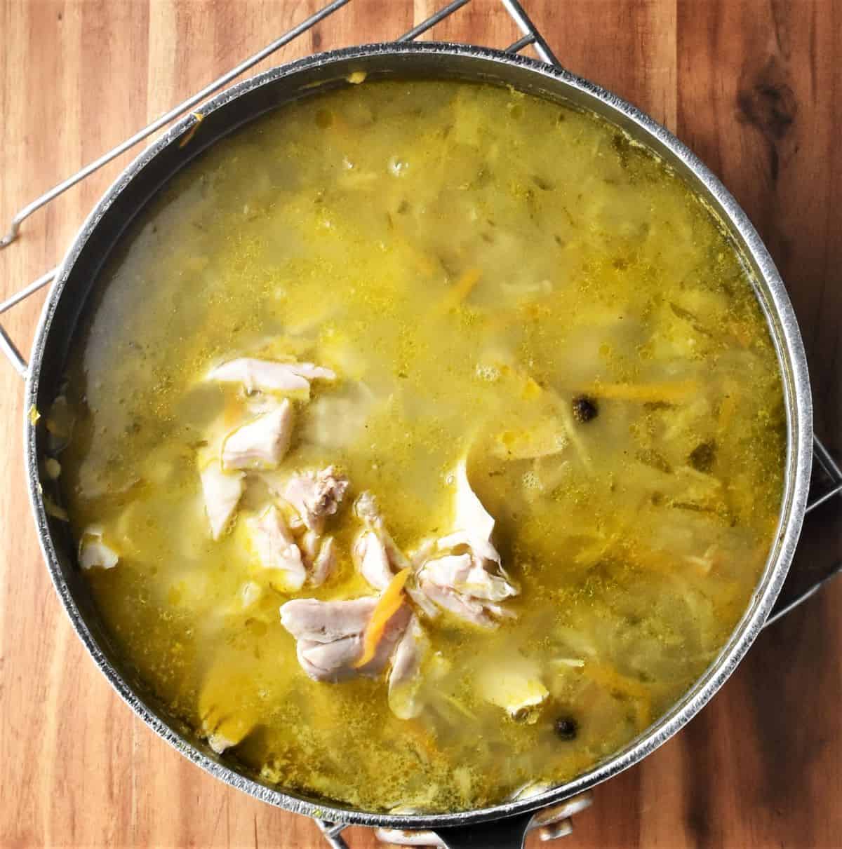 Polish dill pickle soup with chicken pieces in large pot.