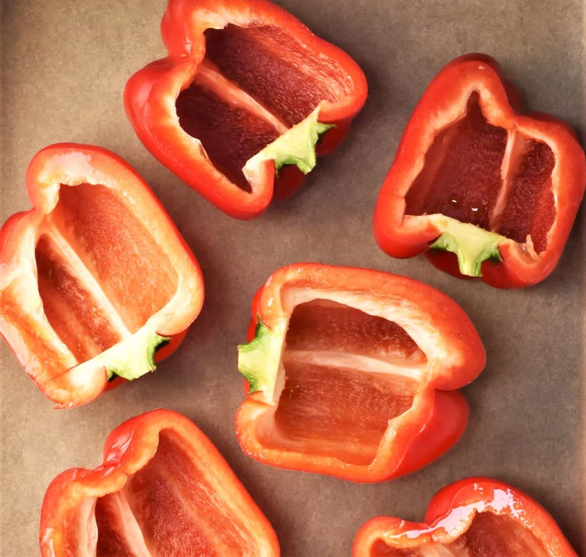 Halved red peppers on top of parchment.