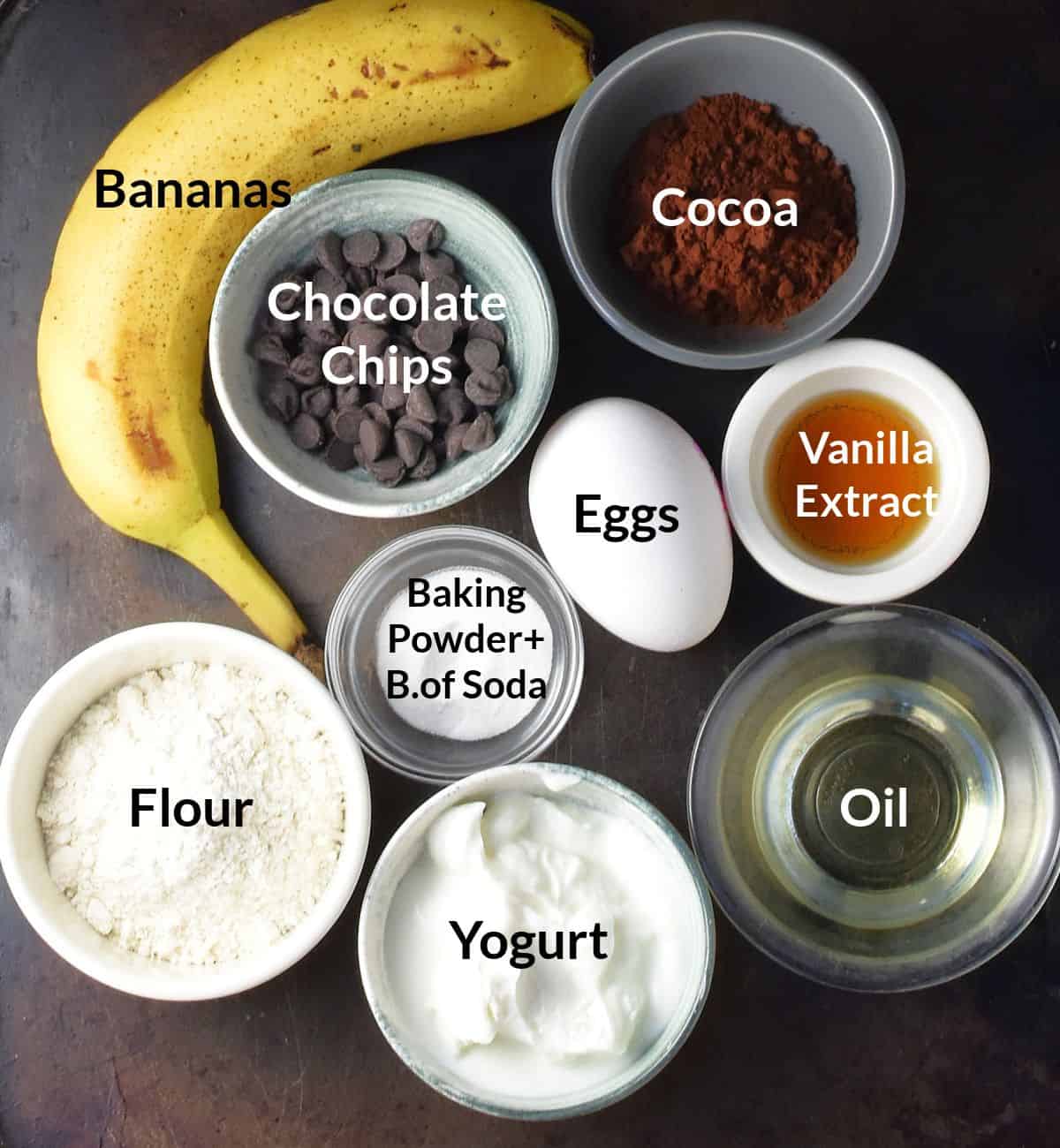 Top down view of chocolate and banana pancake ingredients in individual different sized dishes.