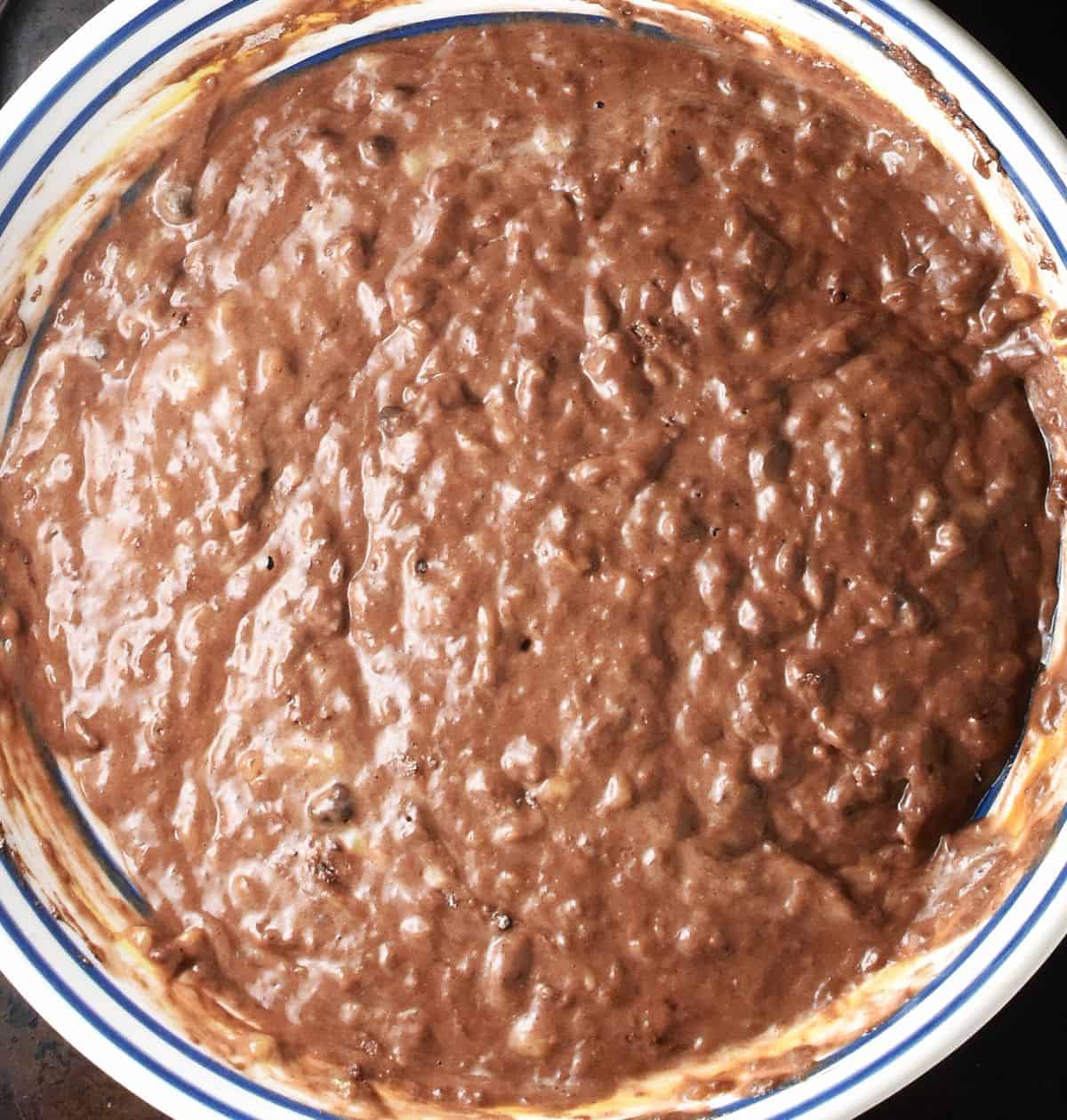 Banana and chocolate pancake batter in stripy shallow bowl.
