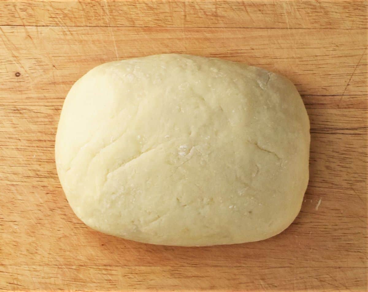 Smooth potato dumpling dough on top of wooden surface.