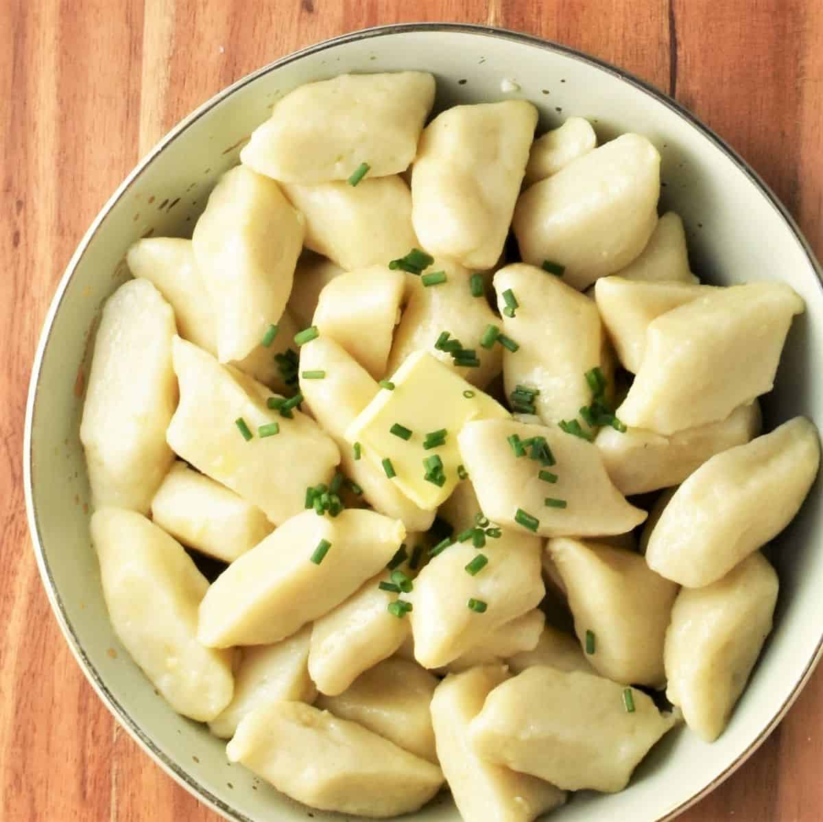 Top down view of potato cooked dumplings in green bowl.