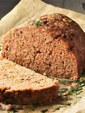 Side view of cut meatloaf with oats on top of parchment.