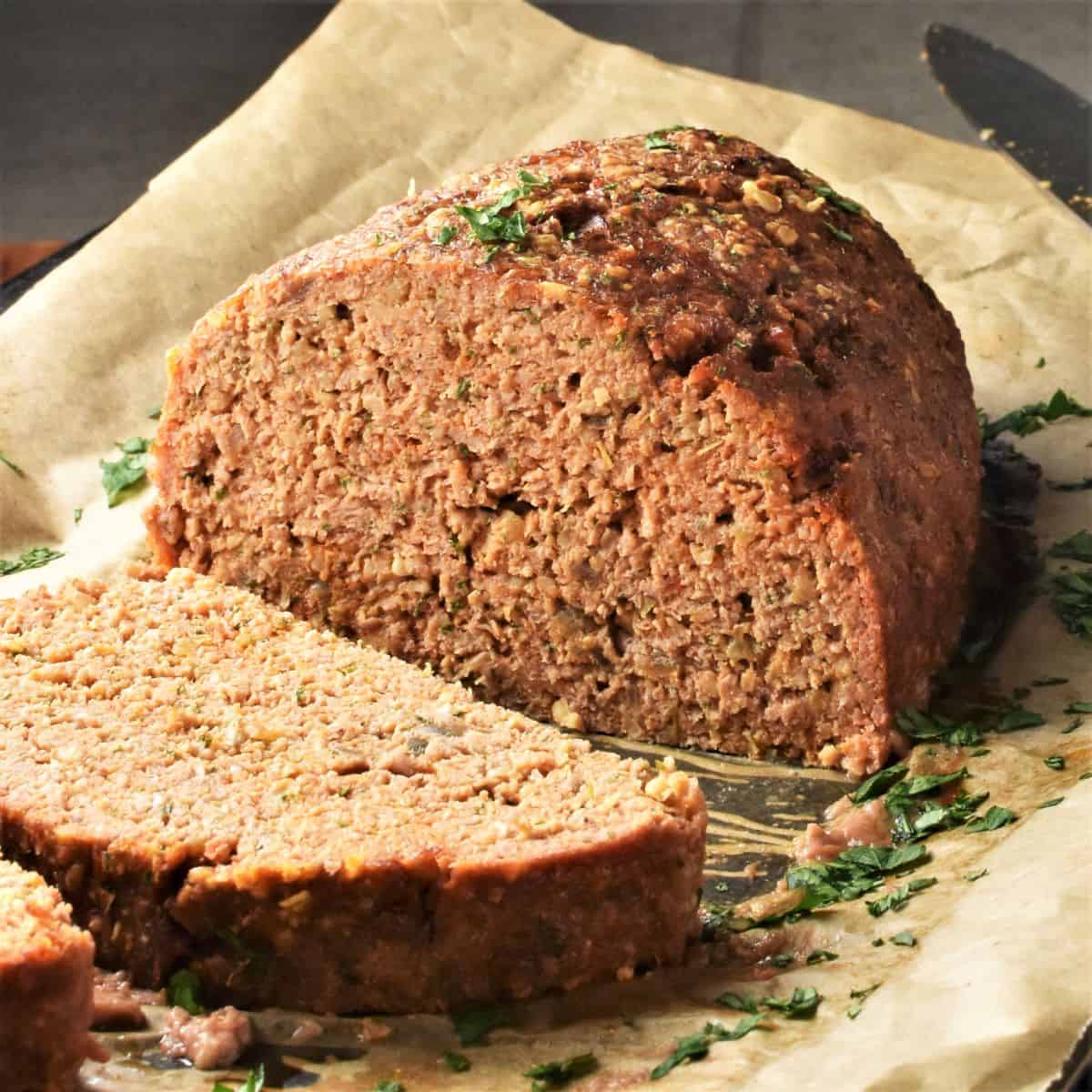 Side view of cut meatloaf with oats on top of parchment.