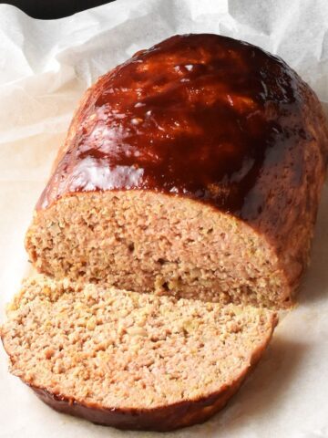 Side view of cut meatloaf with oats and glaze on parchment paper.