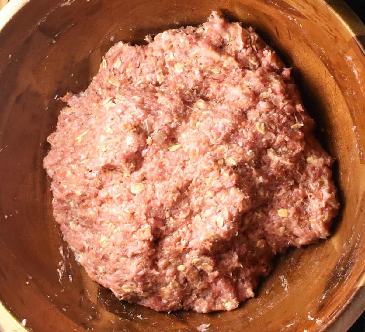 Meatloaf with oatmeal mixture in wooden bowl.