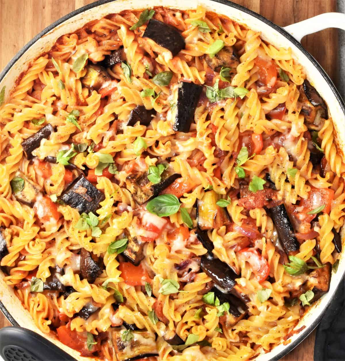 Pasta bake with eggplant in shallow round casserole dish.