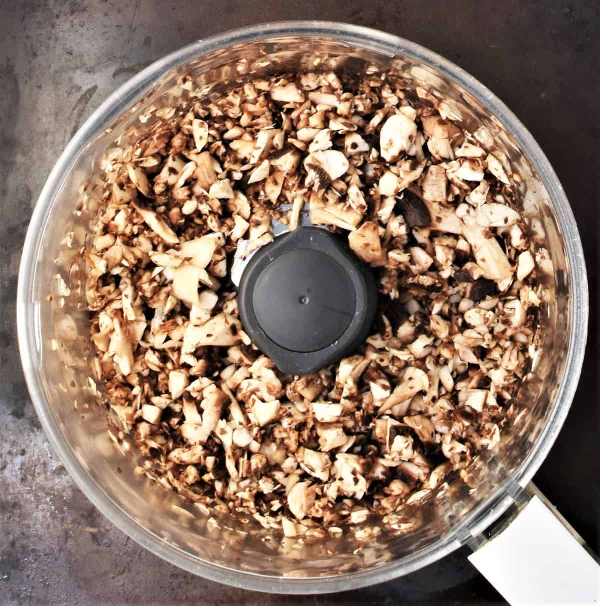 Top down view of chopped mushrooms in blender bowl.